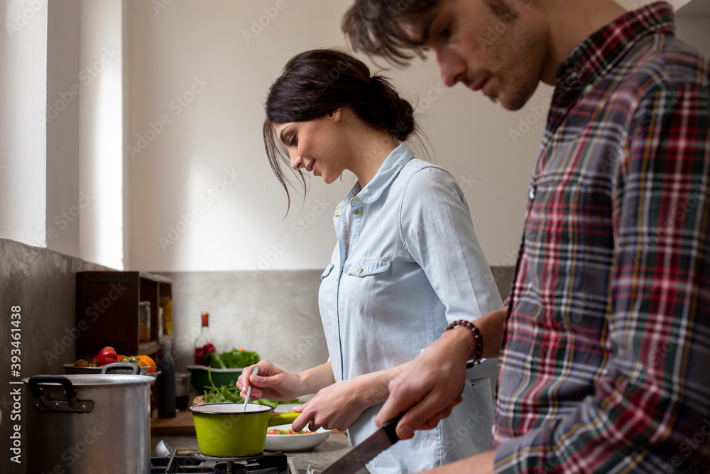 Glad woman preparing sauce near boyfriend Glad woman preparing sauce near boyfriend
