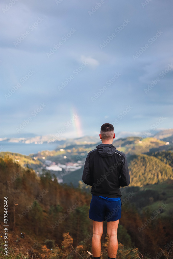 
A person looking for a rainbow at the top of a mountain
