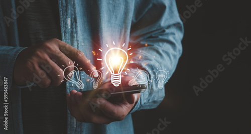 Foto Businessman touching smartphone with light bulbs on the phone screen