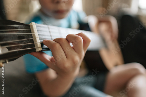 A young boy is learning to play the guitar.