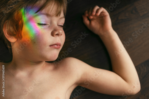 Little boy with rainbow glare on his face. photo