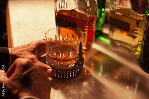 Young man's cropped hand holding a whisky glass. photo