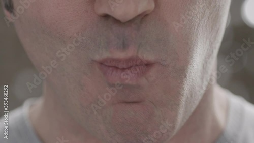Close-up of unidentified cheerful middle-aged man eating meat from a fork on background of blurry sparkles. Refined and healthy nutrition concept. Slow motion