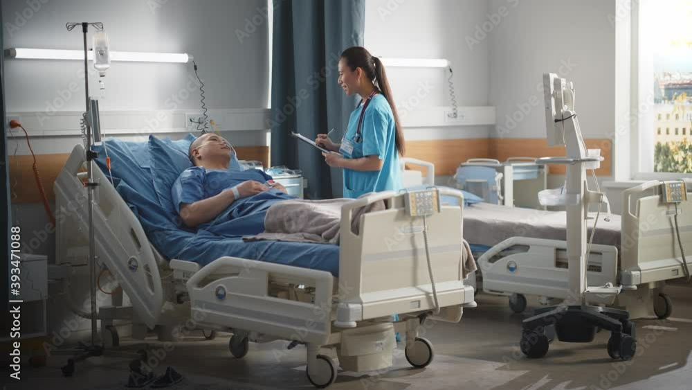 Hospital Ward: Friendly Chinese Head Nurse Fills Medical History Form, Talks to Male Patient Recovering in Bed. Beautiful Professional General Physician / Doctor Helps Man Get Better after Surgery. Hospital Ward: Friendly Chinese Head Nurse Fills Medical History Form, Talks to Male Patient Recovering in Bed. Beautiful Professional General Physician / Doctor Helps Man Get Better after Surgery.