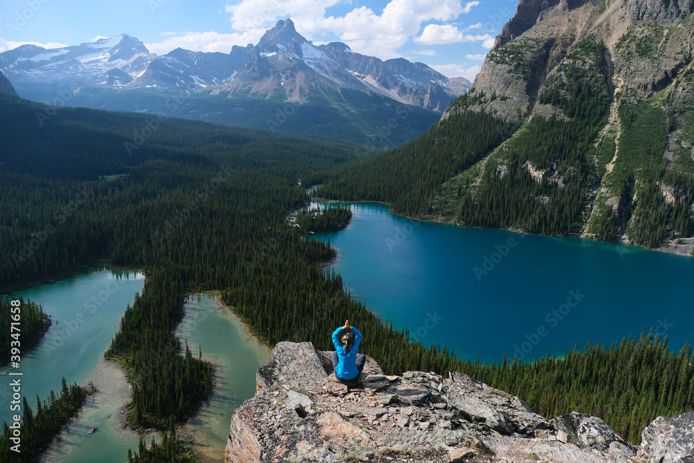 Middle age woman hiker on cliff above blue lakes in Yoho National Park. Lake O'Hara. British Columbia. Canada 
