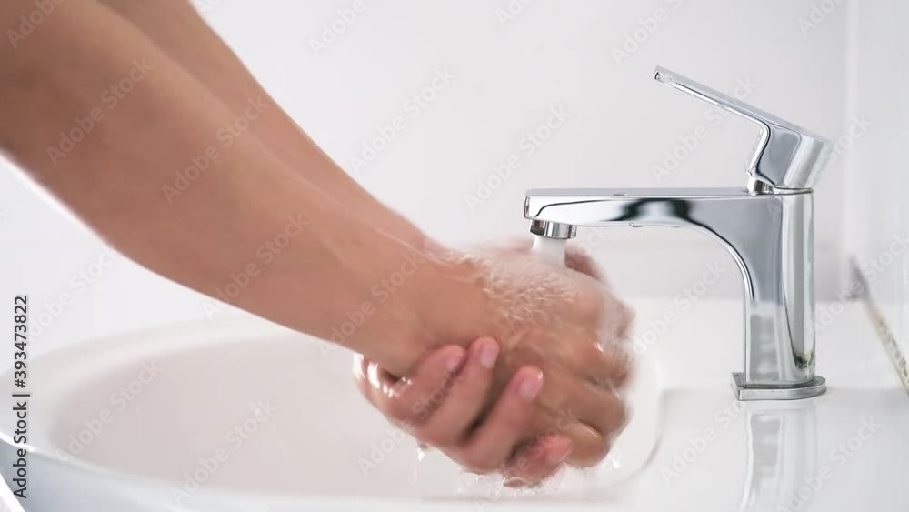 Hands of woman wash their hands in a sink with foam to wash the skin and water flows through the hands. Concept of health, cleaning and preventing germs and coronavirus from contacting hands Hands of woman wash their hands in a sink with foam to wash the skin and water flows through the hands. Concept of health, cleaning and preventing germs and coronavirus from contacting hands