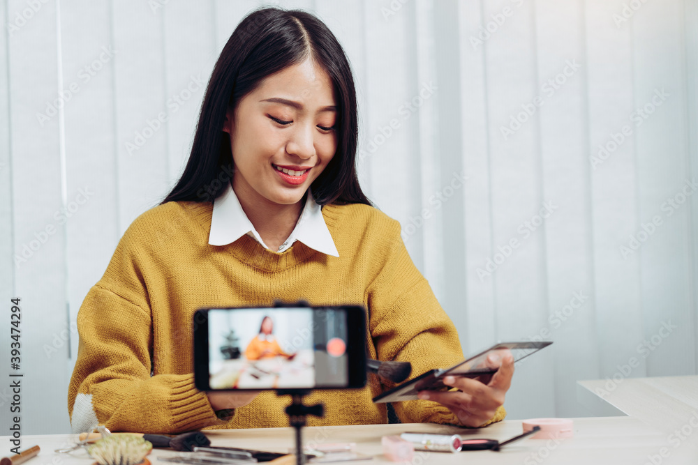 Beautiful asian woman blogger using camera phone recording vlog video live streaming and showing how to make up cosmetics at home. Beautiful asian woman blogger using camera phone recording vlog video live streaming and showing how to make up cosmetics at home.