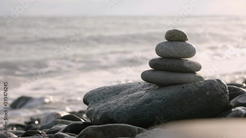 Stack of pebble stones in front of  sea with coming waves.