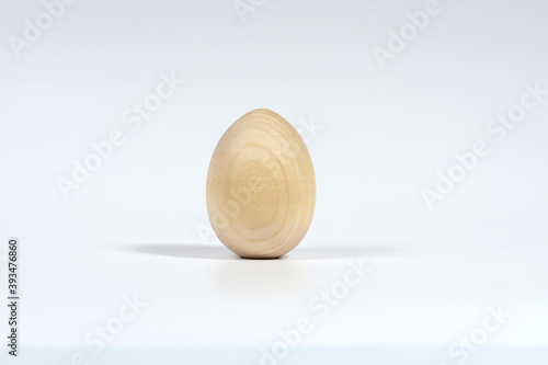 One vertical unpainted wooden egg isolated on a white background with a soft shadow. The Concept Of A Happy Easter.