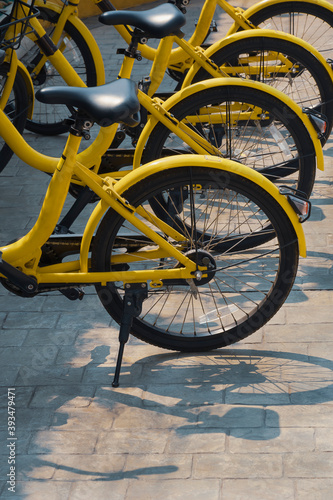 Part of yellow bicycles parked on cobblestone pavement in vertical frame