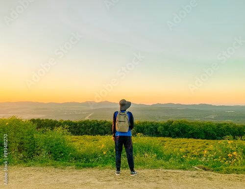 Young man asian traveler looking view sunset on Tung Bua Tong, Mae Moh, Lampang, Thailand. Mexican sunflower field. Travel concept © Tanawat Thipmontha
