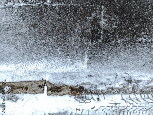 snowy winter road with thin layer of snow and imprints of tire tracks