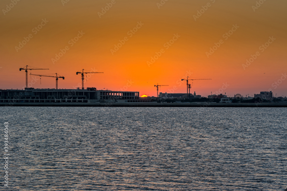 Landscape of sun rising over the construction site with crane in the sea in the morning in Dammam, Kingdom of Saudi Arabia