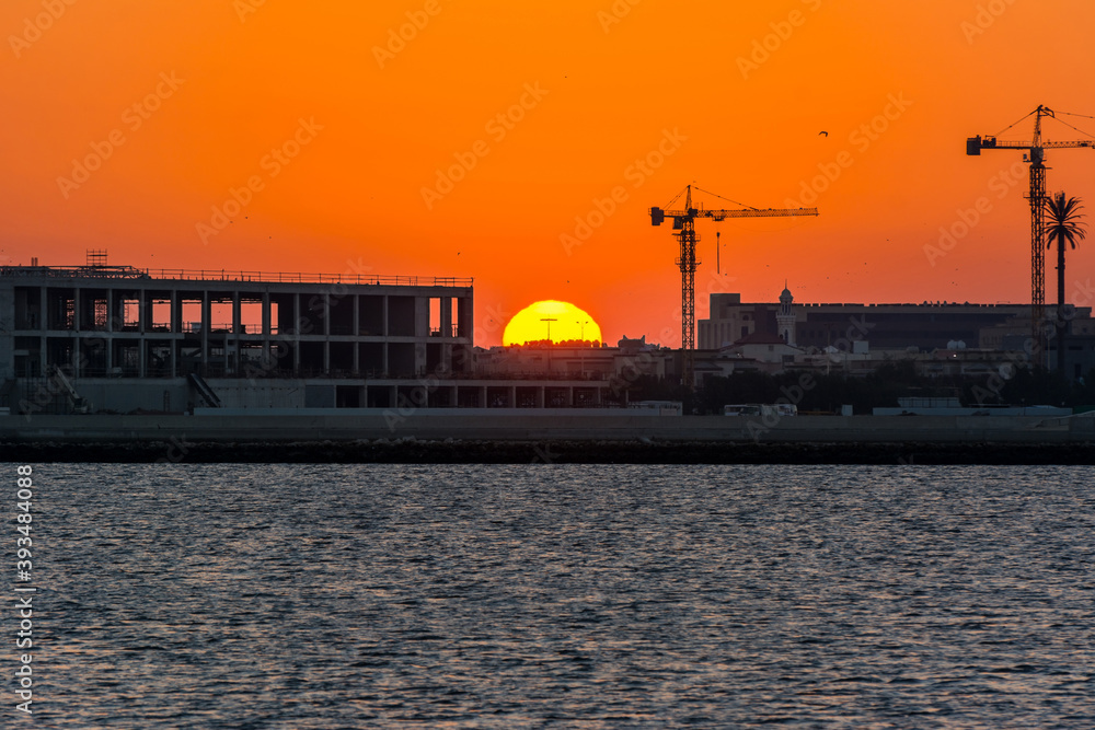 Landscape of sun rising over the construction site with crane in the sea in the morning in Dammam, Kingdom of Saudi Arabia