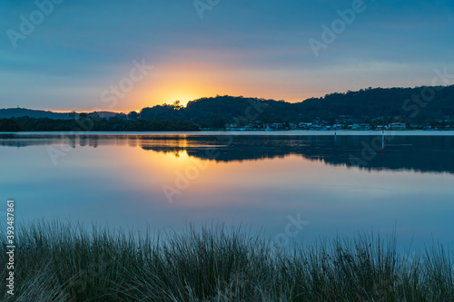 Reflection of Sunrise with soft high cloud over the waterfront