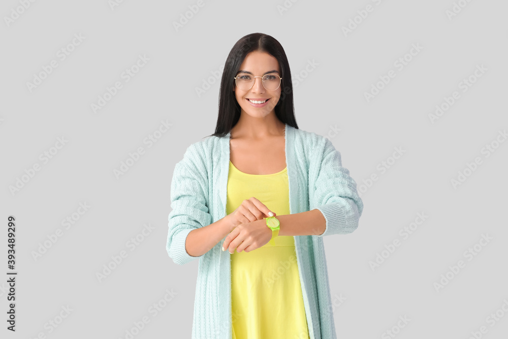 Young woman with wristwatch on grey background Young woman with wristwatch on grey background