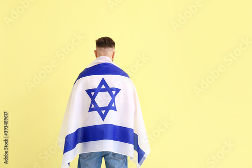 Man with the flag of Israel on color background, back view photo