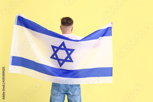 Man with the flag of Israel on color background, back view photo