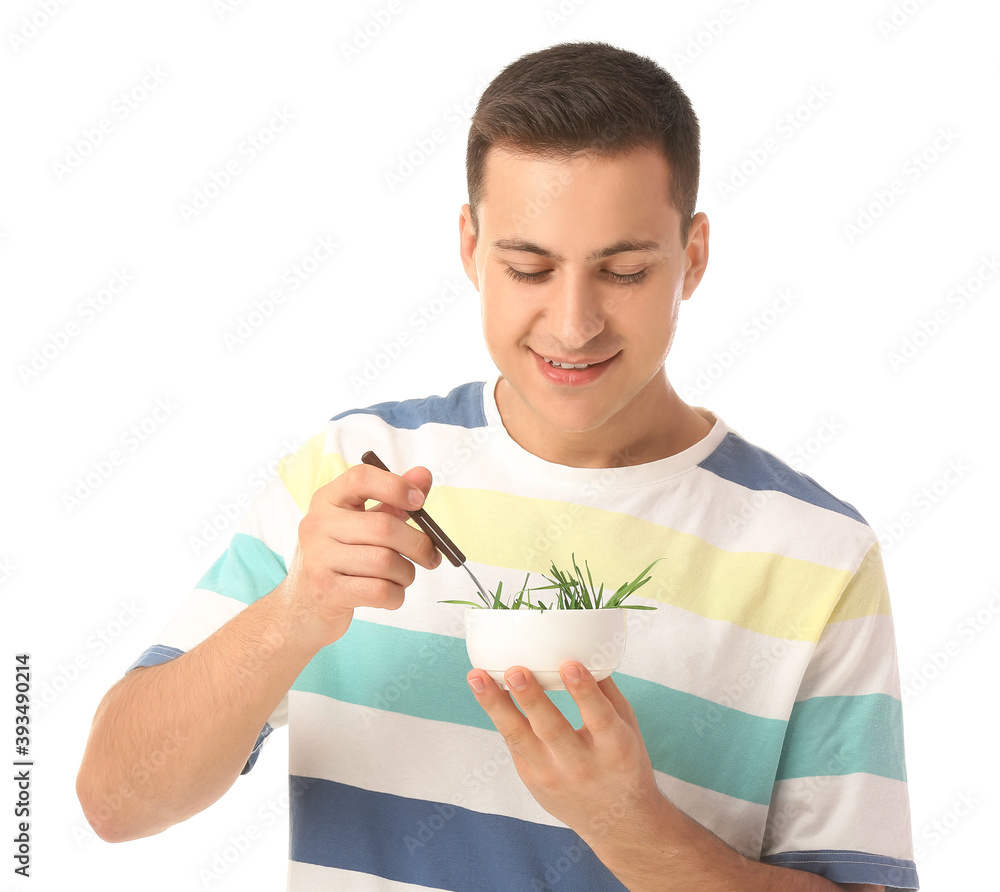 Young man eating wheatgrass on white background Young man eating wheatgrass on white background