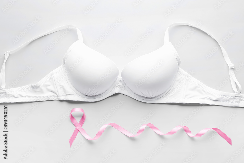 Pink ribbon and bra on light background. Breast cancer awareness concept Pink ribbon and bra on light background. Breast cancer awareness concept