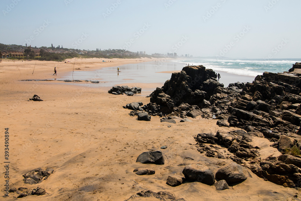 Black Rocks on Beach with Fishermen in Background