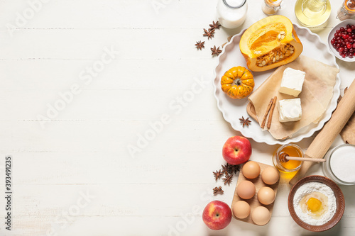 Ingredients for preparing pumpkin pie on white wooden background