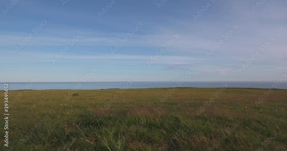 Meadow on Top of Hill in The Summer Evening to The Baltic Sea, In South Sweden Skåne Österlen Kåseberga Near Ales Stenar, Aerial Low From Close To Ground To Far From Sea Level Meadow on Top of Hill in The Summer Evening to The Baltic Sea, In South Sweden Skåne Österlen Kåseberga Near Ales Stenar, Aerial Low From Close To Ground To Far From Sea Level