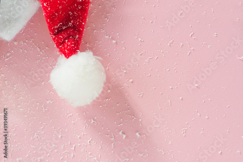 Part of a Santa Claus hat on a pink snow-covered background.