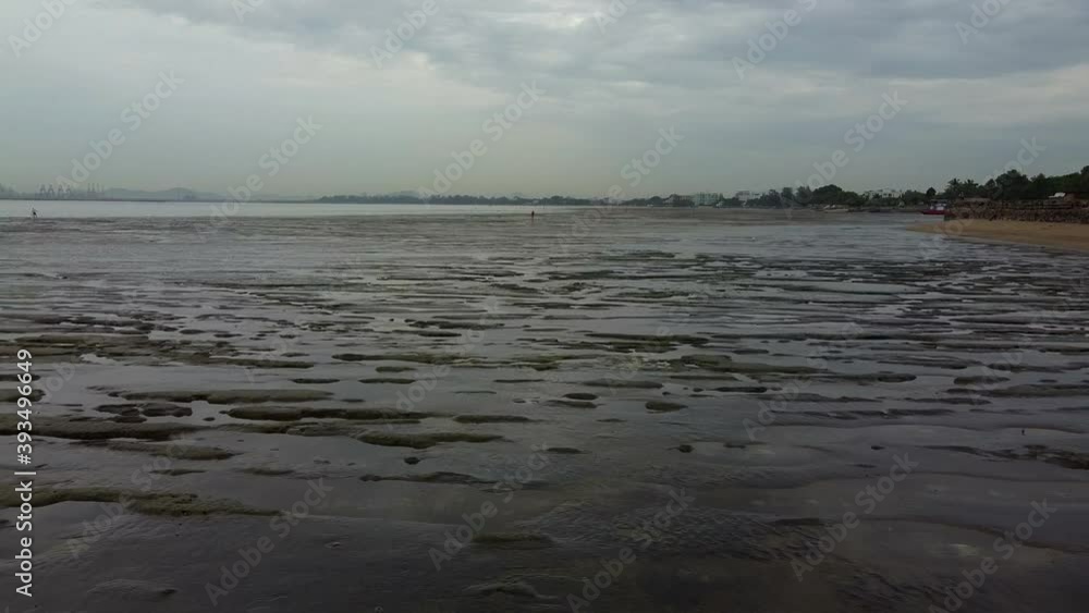 Fly backwards along mud flats under concrete Buddhist sea temple pier Fly backwards along mud flats under concrete Buddhist sea temple pier