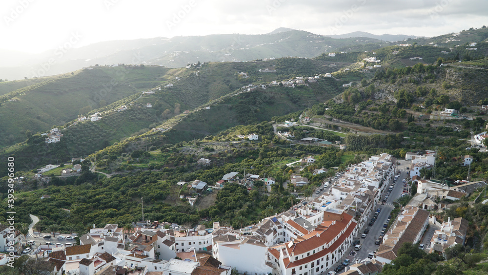 Nerja village architecture with white painted houses in a green hill landscape along the Costa del Sol in Spain.