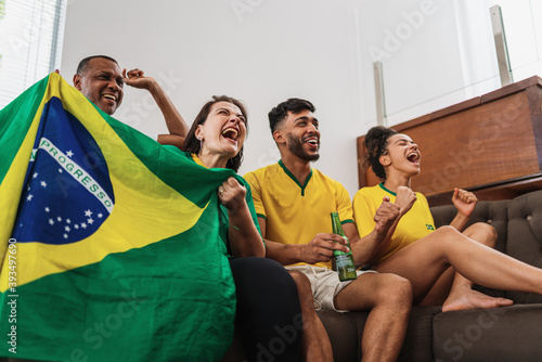 real latin american family watching football on television, celebrating goal of brazil photo