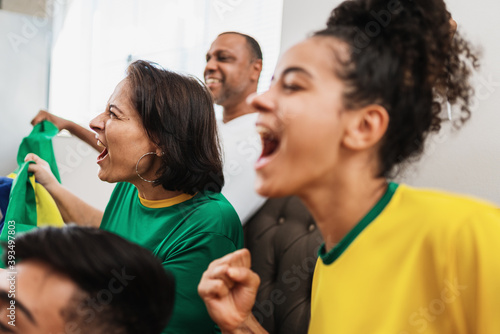 real latin american family watching football on television, celebrating goal of brazil