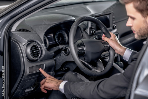 Young male holding steering wheel, pressing control buttons © zinkevych