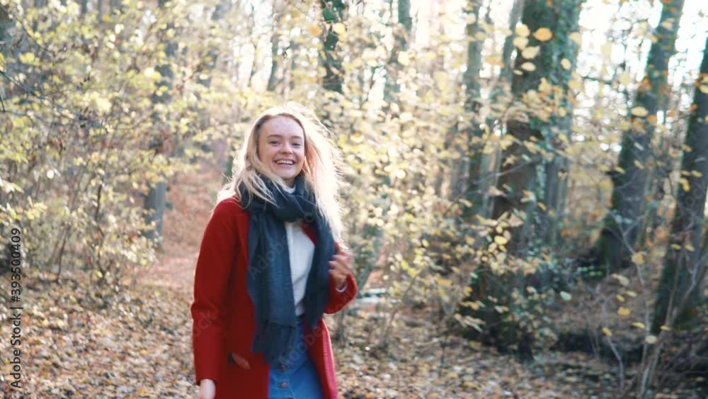 Young beautiful woman throwing leaves in the air amidst thee orange brown autumn forest woodland while wearing a red coat. Young beautiful woman throwing leaves in the air amidst thee orange brown autumn forest woodland while wearing a red coat.