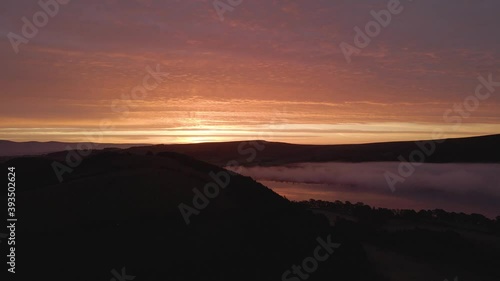 Orange sunrise over cloud inversion in the Lake District, aerial pan up photo