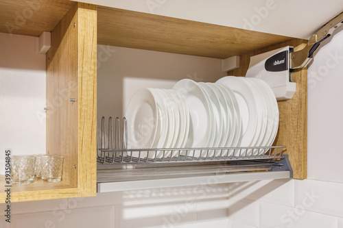 Fotografie set of plates, cups on the shelf in the kitchen cabinet