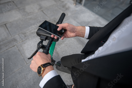 Close up picture of mans hands holding a handle bar and smartphone