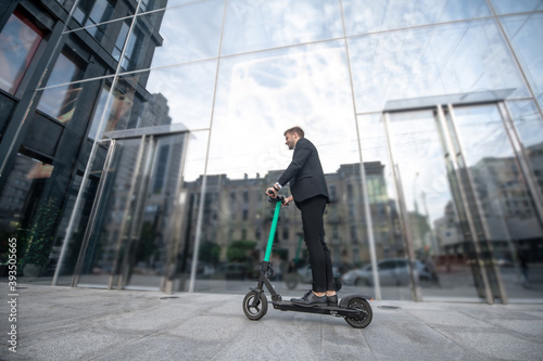 Man on a scooter near a high building