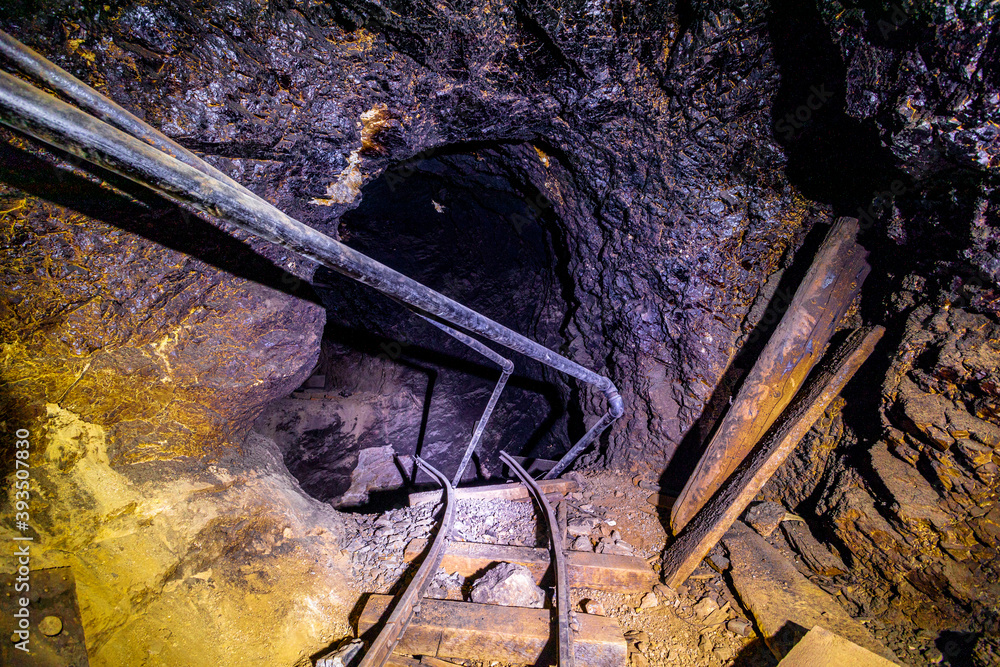 Inside an abandoned mine shaft. Mine cart tracks come to an end due to ...