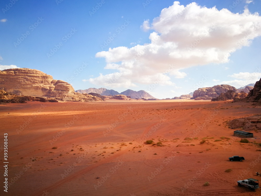 the red desert of Wadi Ram, relief mountains are on the horizon, beautiful clouds in the blue sky, contrasting shadows on the ground the red desert of Wadi Ram, relief mountains are on the horizon, beautiful clouds in the blue sky, contrasting shadows on the ground