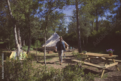 Bild auf Leinwand a man with a backpack on a nature excursion holds a gas lamp in a camp in the wo
