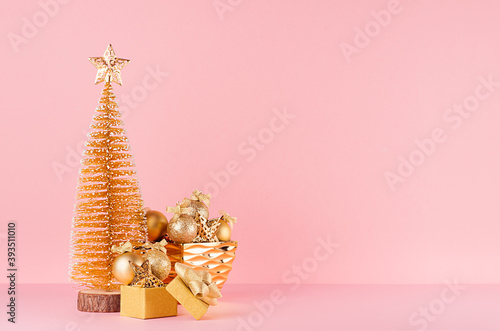 Gold christmas tree with sparkle stars  balls in bowl  gift box on elegant pastel pink background.