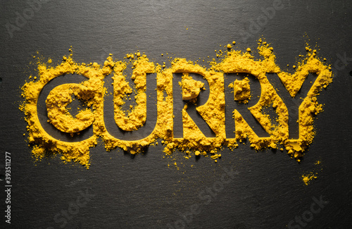Word "Curry" from dry curry powder on black background.