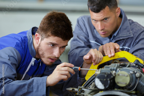 apprentice fixing mechanical part with screw driver