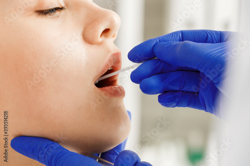 Tableau sur toile Doctor taking a throat swab from a patient woman