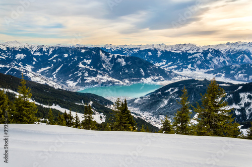 Zell am See and Schmitten town at Zeller lake in winter. View from Schmittenhohe mountain, snowy ski resort slope in the Alps mountains, Austria. Stunning landscape, snow and sunset sky near Kaprun