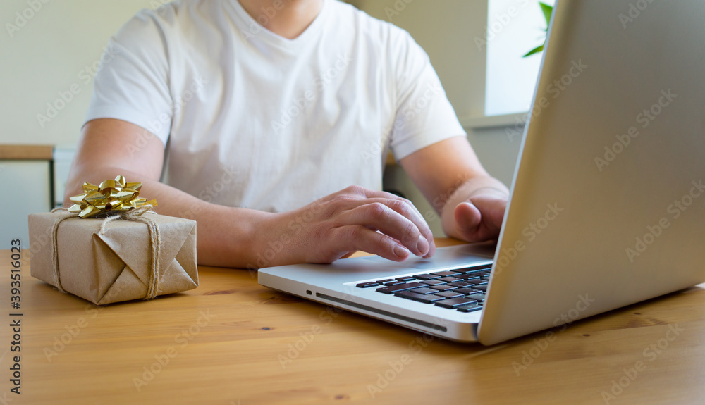 Fototapeta premium A man searches the Internet for gifts on a laptop. Online shopping concept