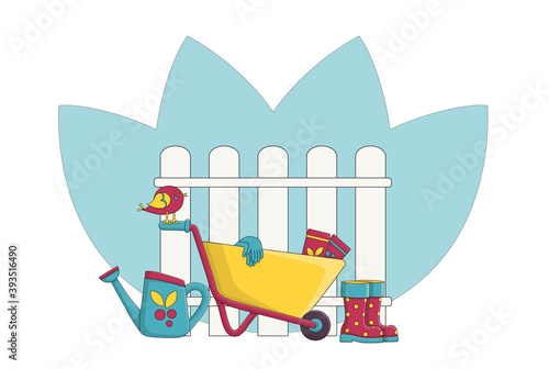 Garden wheelbarrow next to the fence and garden accessories. Concept. Garden supplies. Watering can next to the wheelbarrow and rubber boots. Gardening gloves for planting seeds. Colorful picture