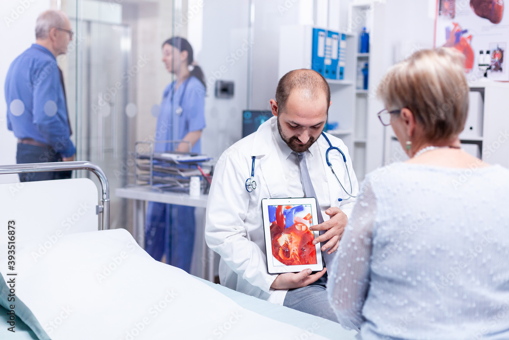 Physician pointing at heart disease using tablet pc and talking with patient about diagnosis. Medical services medicine healthcare well-being support, physician working