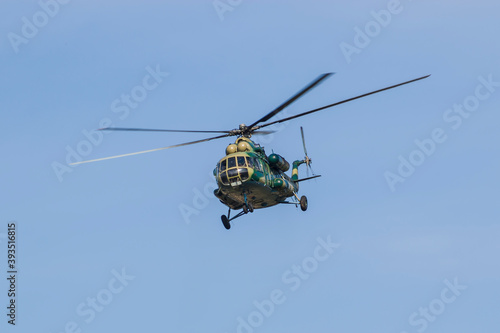 A military helicopter painted in camouflage color is flying high in the sky. Close up.